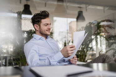 Geschäftsmann, der bei der Arbeit im Büro ein Dokument analysiert - DIGF14713