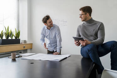 Geschäftsleute, die bei der Arbeit im Büro über einen Bauplan diskutieren - DIGF14715