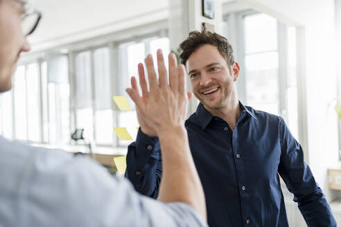 Glückliche männliche Kollegen beim High-Five im Büro - DIGF14747