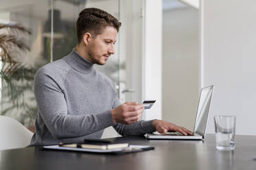 Geschäftsmann, der online mit Kreditkarte auf einem Laptop im Büro bezahlt - DIGF14766