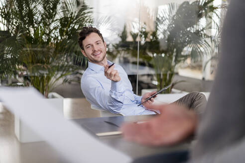 Lächelnder männlicher Unternehmer mit digitalem Tablet im Büro - DIGF14773