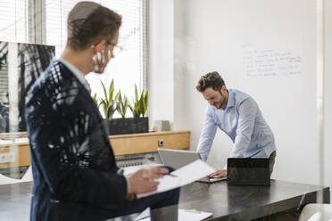 Geschäftsleute durch Glas gesehen bei der Arbeit im Sitzungssaal im Büro - DIGF14786