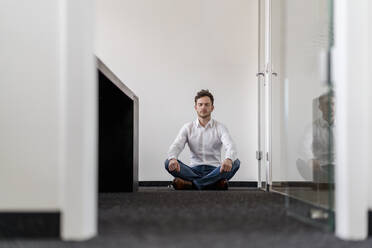Businessman meditating yoga in office - DIGF14788