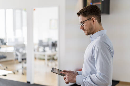 Männlicher Unternehmer, der ein digitales Tablet bei der Arbeit im Büro benutzt - DIGF14797