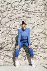 Frau mit kühler Haltung starrt, während auf kahlen Zweig Wand stehen - JSMF02032