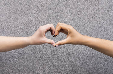 Hands of two young women touching and making heart shape - JCCMF01318