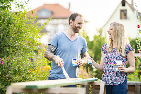 Älteres Paar lachend beim Malen im Garten, lizenzfreies Stockfoto