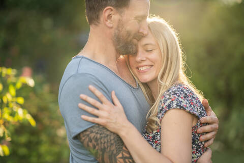 Paar umarmt sich im Garten, lizenzfreies Stockfoto