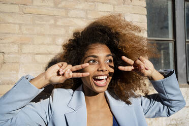 Cheerful Afro woman gesturing against wall - RCPF00748