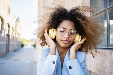 Afro-Frau mit braunem Haar hört Musik über Kopfhörer - RCPF00755