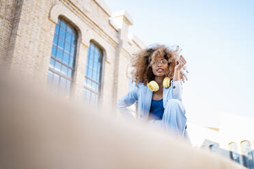 Afro-Frau mit Kopfhörern gegen den Himmel - RCPF00760