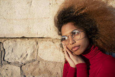 Afro woman wearing sunglasses with hands on chin looking away - RCPF00792