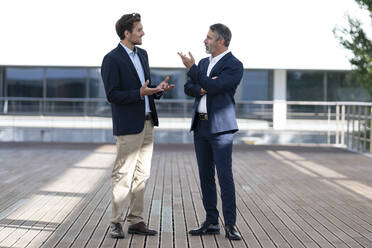 Business people having discussion while standing on office building terrace - SBOF02872