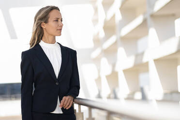 Female entrepreneur looking away while standing at building terrace - SBOF02989