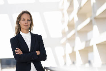 Confident female professional standing with arms crossed at office building terrace - SBOF02990