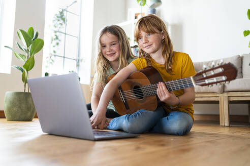 Lächelnde Mädchen e-learning Gitarren-Tutorial durch Laptop im Wohnzimmer zu Hause - SBOF03052