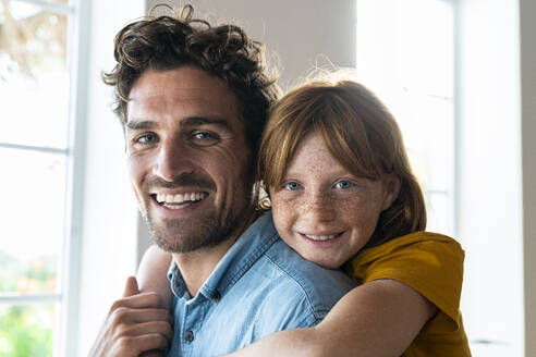 Lächelnde Tochter umarmt fröhlichen Vater zu Hause - SBOF03070