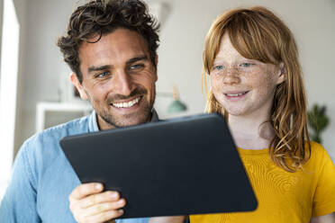 Redhead girl with father looking at laptop at home - SBOF03083