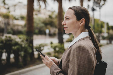 Unternehmerin hält Smartphone und schaut weg - DMGF00486