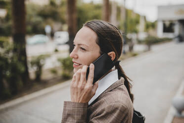 Smiling female professional talking on mobile phone while looking away - DMGF00487