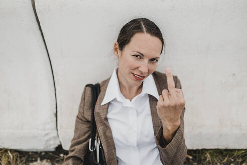 Weiblicher Berufstätiger gestikuliert mit dem Zeigefinger, während er an der Leitplanke sitzt - DMGF00508