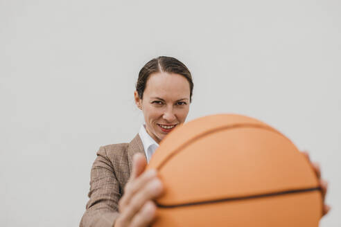Lächelnder weiblicher Profi mit Basketball in der Pause - DMGF00516