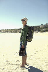 Männlicher Tourist mit Rucksack auf Sand stehend an einem sonnigen Tag - AJOF01157