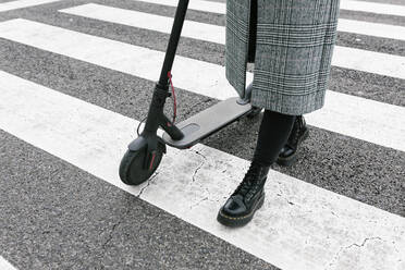 Frau mit Elektroroller zu Fuß auf Zebrastreifen - XLGF01254