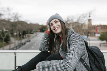 Thoughtful smiling woman sitting outdoors in city - XLGF01261