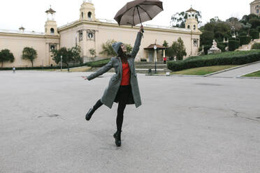Playful woman holding umbrella in city - XLGF01274