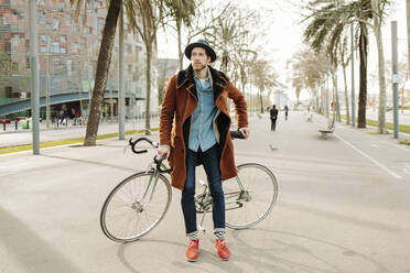 Mittlerer erwachsener Mann mit Fahrrad auf der Straße in der Stadt - GMCF00025