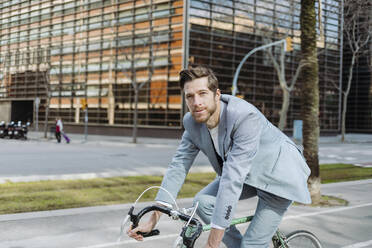 Männlicher Berufstätiger, der in der Stadt mit dem Fahrrad unterwegs ist - GMCF00029