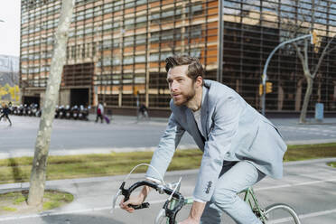 Male commuter riding on bicycle in city - GMCF00030