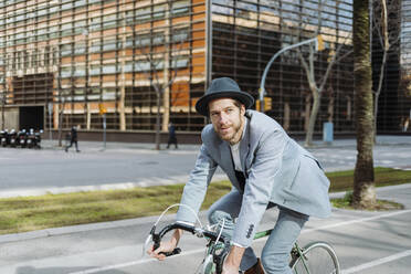 Geschäftsmann mit Hut auf dem Fahrrad in der Stadt - GMCF00031