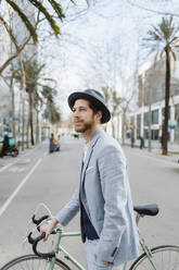 Geschäftsmann mit Fahrrad, der in der Stadt spazieren geht und wegschaut - GMCF00034