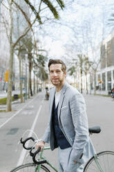 Männlicher Profi mit Fahrrad auf der Straße in der Stadt stehend - GMCF00036