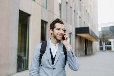 Lächelnder männlicher Berufstätiger, der mit dem Handy telefoniert und dabei wegschaut - GMCF00039