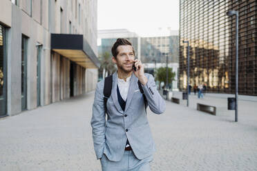 Male entrepreneur talking on mobile phone while standing on road in city - GMCF00041