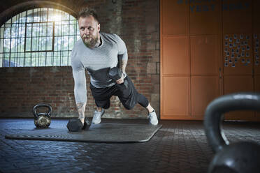 Active sportsman exercising with dumbbell in gym - RORF02660