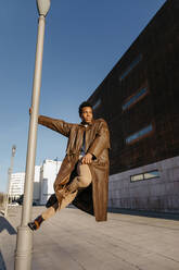 Male dancer climbing on lamppost in city during sunset - TCEF01616