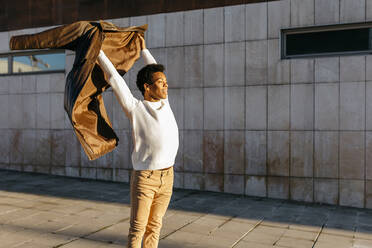 Männlicher Tänzer mit Jacke vor einem Gebäude - TCEF01623