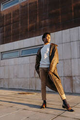Männlicher Tänzer, der bei Sonnenuntergang vor einem Gebäude steht - TCEF01636