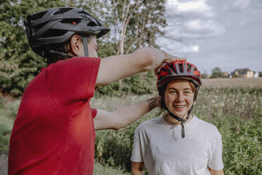 Vater hilft Tochter beim Tragen eines Fahrradhelms - OGF00918