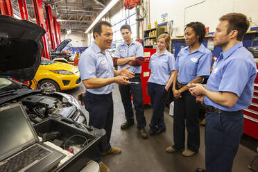 Männer und Frauen mit unterschiedlichem ethnischen Hintergrund, ein Team von Mechanikern in einer Autowerkstatt - MINF15845