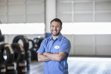 Portrait of a smiling Caucasian male mechanic in an auto repair shop - MINF15850