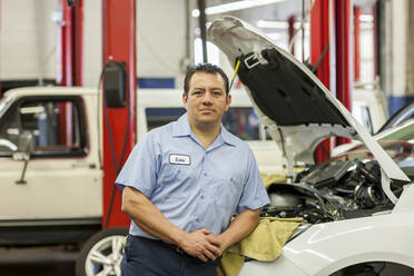 Porträt eines hispanischen männlichen Mechanikers in einer Autowerkstatt - MINF15865