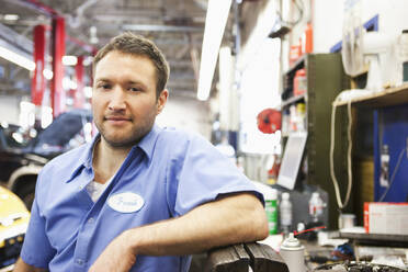 Portrait of a smiling Caucasian male mechanic in an auto repair shop - MINF15876