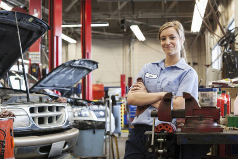 Porträt einer jungen kaukasischen Mechanikerin in einer Autowerkstatt - MINF15896