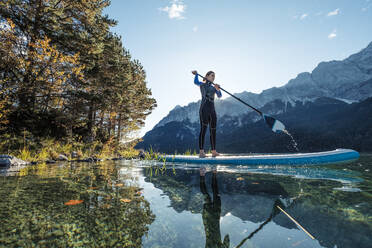 Germany, Bavaria, Garmisch Partenkirchen, Young woman stand up paddling on Lake Eibsee - WFF00473