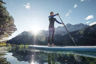 Germany, Bavaria, Garmisch Partenkirchen, Young woman stand up paddling on Lake Eibsee - WFF00474